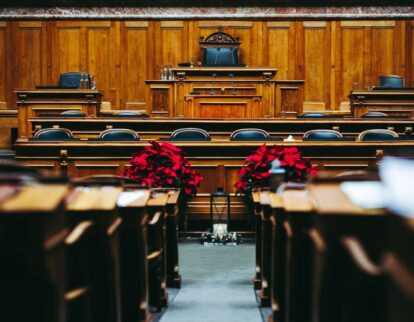 Leerer Sitzungssaal im Rathaus mit Rednerpult und roten Blumen
