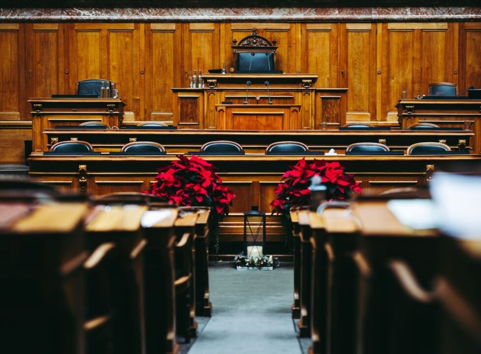 Leerer Sitzungssaal im Rathaus mit Rednerpult und roten Blumen