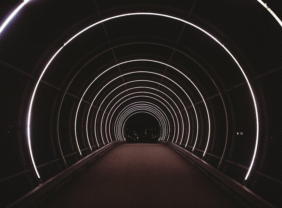 Dunkler Fußgängertunnel mit konzentrischen weißen Neonringen